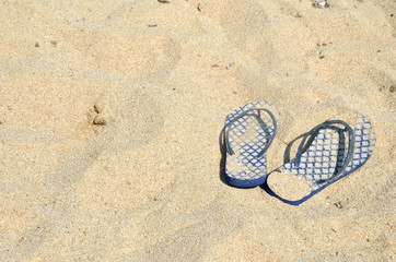 Fototapeta na wymiar Blue flip flops on golden sandy beach