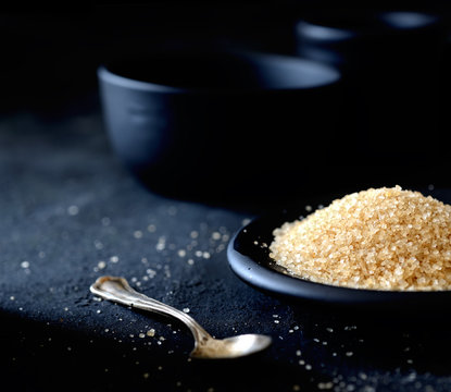 brown sugar in a saucer on the black background
