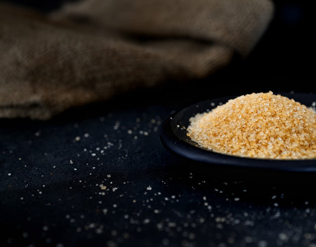 brown sugar in a saucer on the black background
