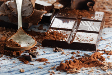 Broken dark chocolate and chocolate shavings on a wooden table