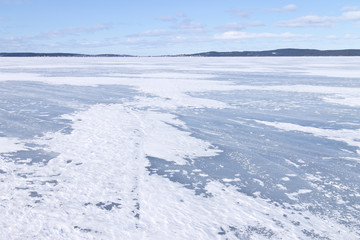 The surface of the lake covered with ice and blowing snow