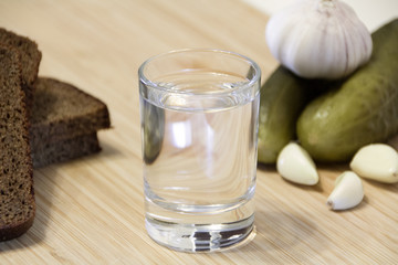Shot of vodka and appetizer on a wooden table