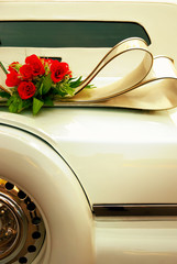 Limousine backside ornate with flowers. White wedding retro car closeup. Yellow toned.
