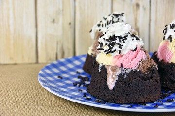 Neapolitan ice cream in brownie bowl on checkered plate