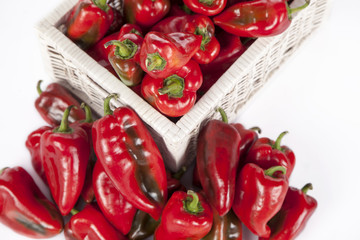 Red bell peppers in a wooden wicker basket isolated on white
