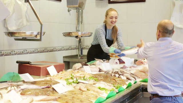 Seller helping customer choosing chilled fish in fishery