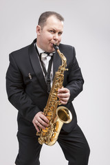 Fototapeta premium Portrait of Expressive Caucasian Player in Suit Playing on Saxophone