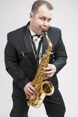 Obraz na płótnie Canvas Portrait of Expressive Caucasian Player in Suit Playing on Saxophone