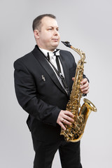 Man with Saxophone in Suite Posing Against White Background.
