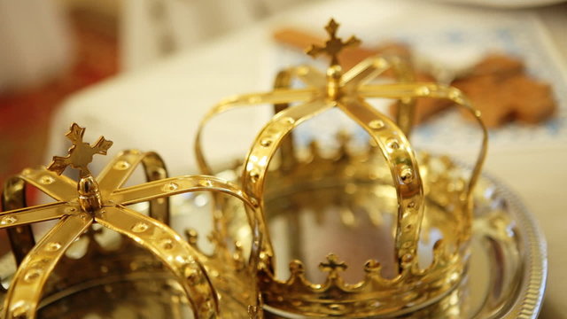 Close up of two gold wedding crowns prepared for ceremony  of marriage in a  church.
