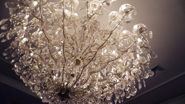 Beautiful retro luxury crystal strass chandelier isolated on a white wall of the restaurant.