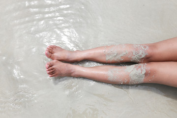 leg or bare woman feet in the ocean on sand beach