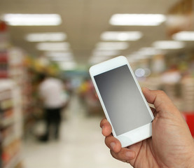 hand holding the smartphone on supermarket in blurry for backgro
