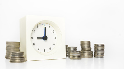 Table clock and multiple stacks of coins. Tme and money concept