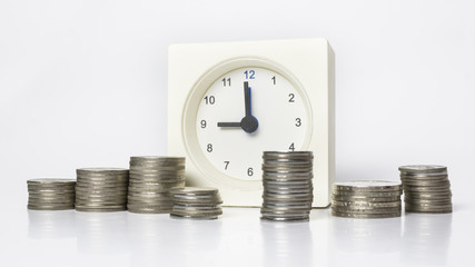 Table clock and multiple stacks of coins. Tme and money concept