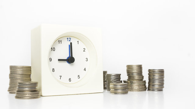 Table clock and multiple stacks of coins. Tme and money concept