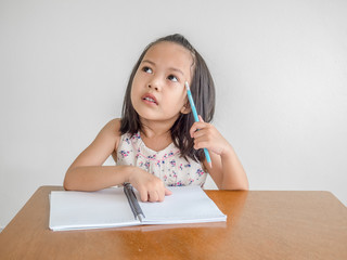 Close up happy adorable asian children thinking something to write on notebook