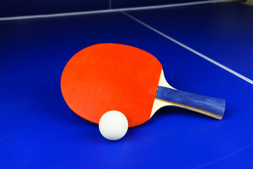 White Table Tennis Ball and a Red Racket on a Blue Table