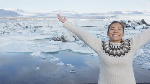 Happy woman in nature with raised arms outstretched. Joyful girl raising arms in serene pose facing Jokulsarlon glacial lagoon, Vatna glacier, Vatnajokull National Park, Iceland. RED EPIC, 96 FPS.