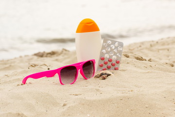 Pink sunglasses, shells, lotion and pills of vitamin E, seasonal concept
