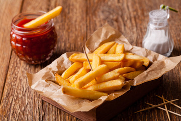 Fresh fried french fries with ketchup on wooden background