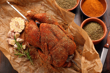 Whole raw chicken with spices ready for roasting on a spit