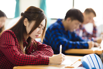 female college student sitting and exam in the classroom - obrazy, fototapety, plakaty
