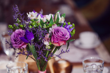 Flowers composition in restaurant,  roses and irises, combination shades of purple