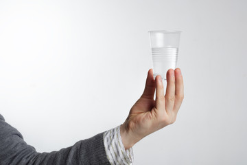 Man holding a disposable plastic cup with water. The lack of dri