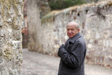 Elderly man standing at the city walls of a historic German town and looking back over his shoulder