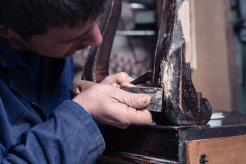 Carpenter restoring Wooden Furniture with plaster and putty Knif