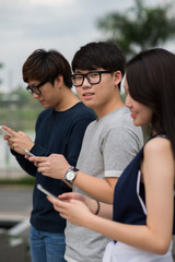 Korean young people with mobile phones standing outdoors