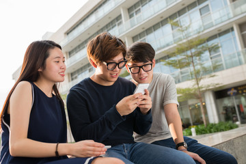 Asian teenagers looking how their friend playing game on his phone