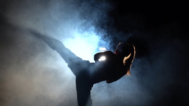 Karate girl kicks. Black. Silhouette. Backlight