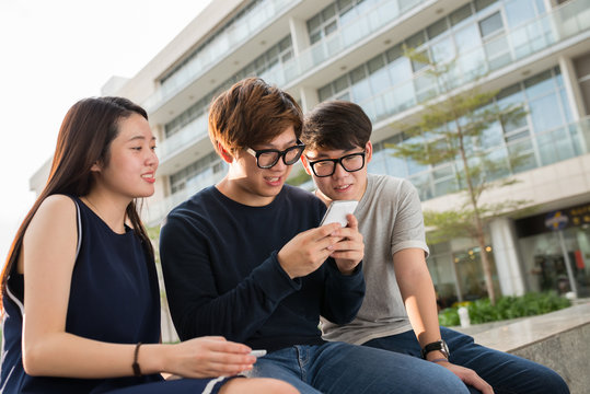 Asian Teenagers Looking How Their Friend Playing Game On His Phone