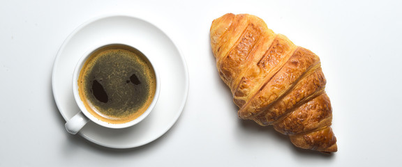 Overhead view of cup of black coffee and freshly croissant