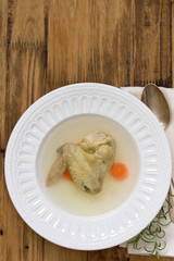 chicken broth on white plate on brown background