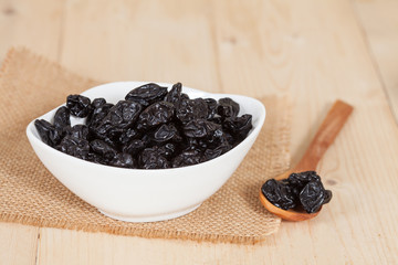Raisin in the bowl on the wood background