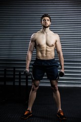 Fototapeta premium Front view of serious man lifting weight