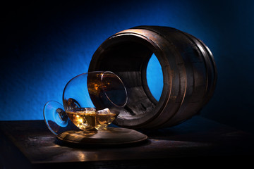 A glass of brandy and ice on a background of empty oak barrels