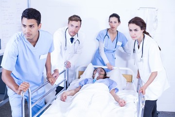 Concerned doctors standing near patient on bed