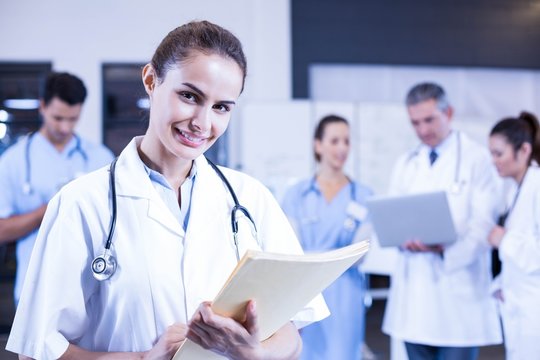 Female doctor holding medical report and smiling 