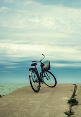 Bicycle at the beach on cloudy sky background. vintage retro sty