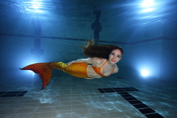 Mermaid swimming underwater in the pool 