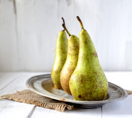 pears on a plate on white wooden background