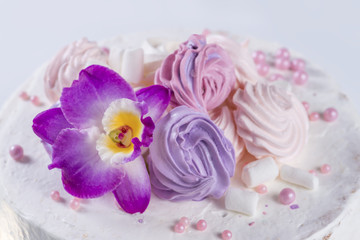 orchid flower on the cake with white cream and marshmallows