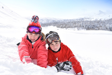 Fototapeta na wymiar Kids at ski resort laying down in snow