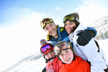 Portrait of happy family of 4 in snowy mountains