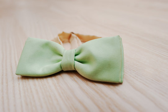 Lime silk bow tie on light wooden background
