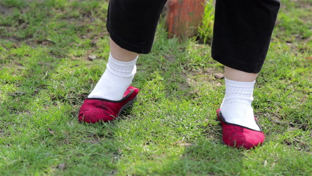 feet in white socks/legs with white socks and stand on the grass in slippers